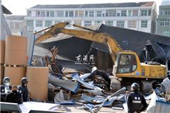 龙港网12月29日讯：918名学生“蜗居”几亩校园数年，眼看10亩操场用地出租期满，打算收回新建操场。却因龙港镇新城社区黄库村以此地系村里资产为由，继续对外出租，几度争议搁置一年无果。 今天上午，龙港镇两违办对仓库进行了彻底拆除。